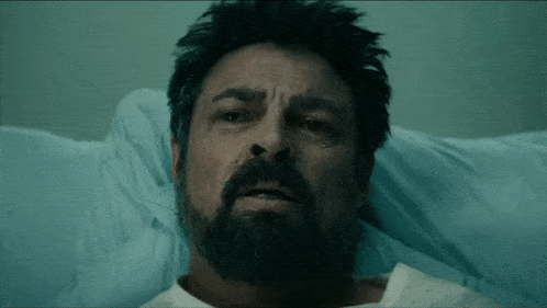 a man with a beard is in a hospital bed with his eyes closed