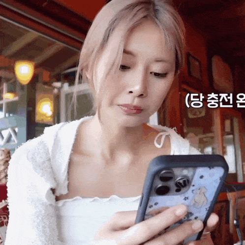a woman in a white top is holding a cell phone with a case that says ' snoopy ' on it