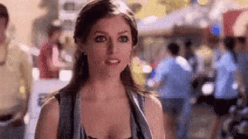 a woman is standing in front of a crowd of people in a crowded area .