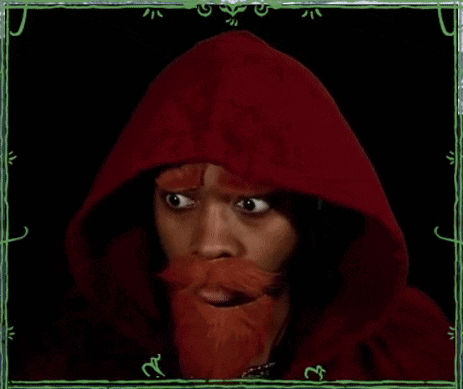 a man with a red beard and a red hood is making a funny face with his hands .