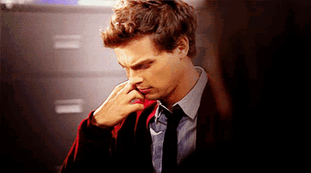 a man in a suit and tie holds his hand to his nose