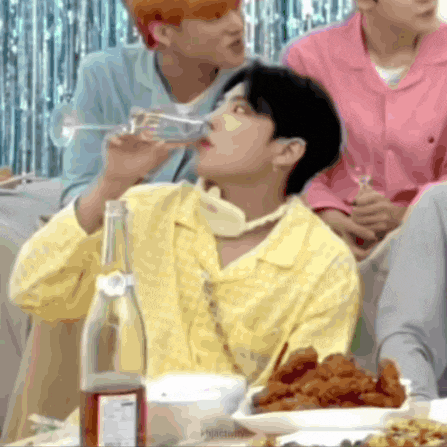 a man in a yellow shirt drinking from a glass