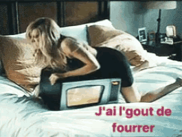 a woman laying on a bed with a microwave and the words j ' ai l ' gout de fourrer