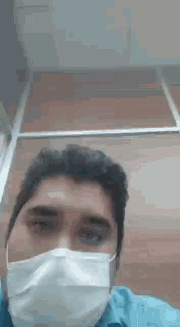 a man wearing a mask is looking at the camera while standing in an elevator .