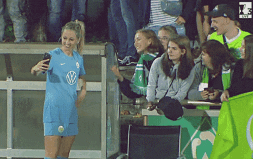 a woman in a vw shirt takes a selfie with her phone