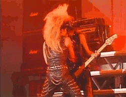 a woman is playing a guitar on a stage while a man is playing a bass guitar .