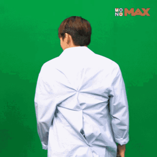 a man in a white shirt is standing in front of a green screen that says max