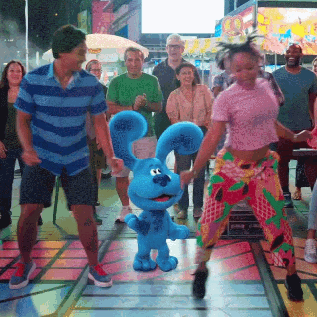 a group of people dancing with a blue bunny in the middle