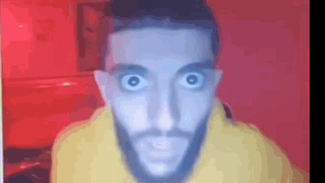 a man with a beard is making a funny face while wearing a yellow hoodie .