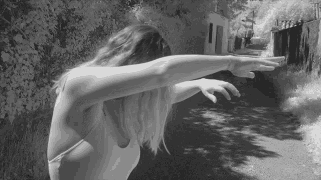 a black and white photo of a woman with her arms outstretched in front of a building