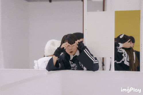 a girl wearing a hoodie that says ' yju ' on it looks out a window