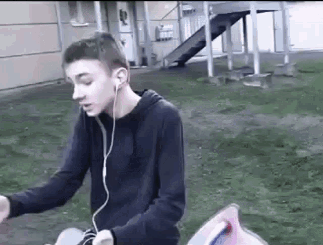 a young man is wearing headphones while sitting on the grass .