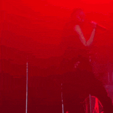 a group of people are standing on a stage with red lights