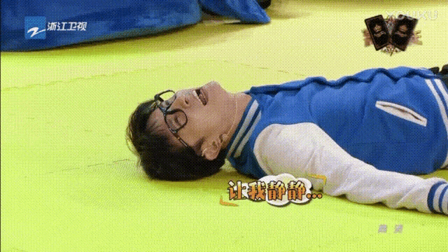 a man in a blue jacket is laying on the floor .