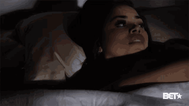 a woman laying on a bed with a bet logo in the background