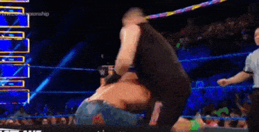 a wrestler is carrying another wrestler on his back in a wrestling ring .