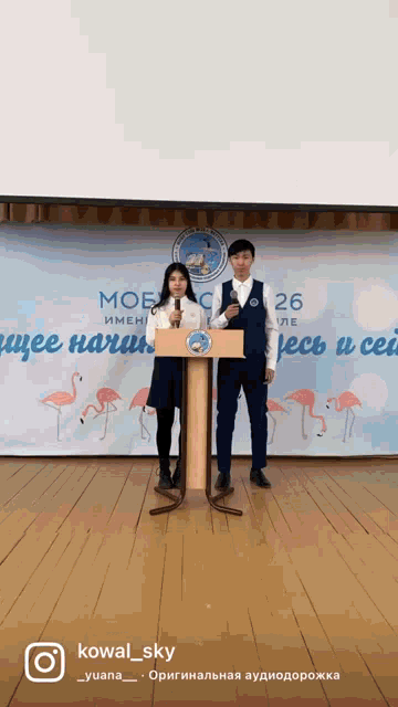 a man and a woman stand at a podium in front of a banner that says mob on it
