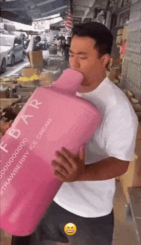 a man in a white shirt is holding a large pink bottle of strawberry ice cream