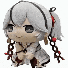 a stuffed animal of a girl with white hair and red ribbons is sitting down .