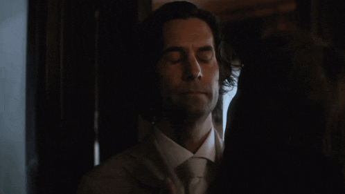 a man in a suit and tie is standing next to a woman with his eyes closed