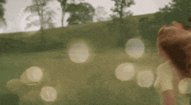 a woman in a white dress is standing in a field of tall grass .
