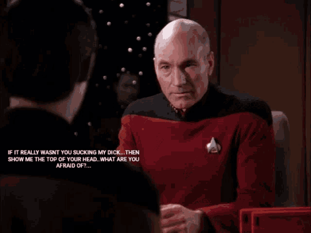 a man in a red shirt is covering his face with his hands while another man talks to him