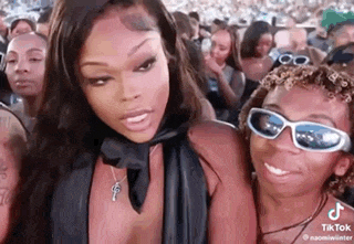 a woman wearing sunglasses is standing next to a man in a crowd .