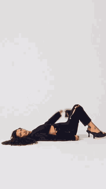 a woman is laying on her stomach holding a black bag