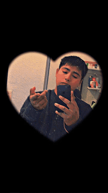 a man taking a picture of himself in a heart shaped frame