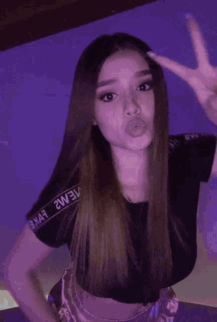 a woman making a peace sign with her tongue out wearing a shirt that says 2we