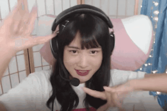 a girl wearing headphones and a microphone is making a heart shape with her hands