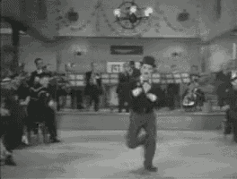 a black and white photo of a man dancing in a room with a band in the background .