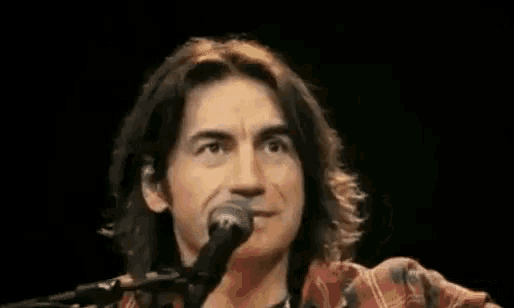 a man with long hair is singing into a microphone and saying `` i personalmente non ho niente contro sanremo '' .