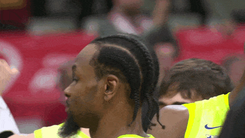 a man wearing a yellow nike jersey with braids on his hair