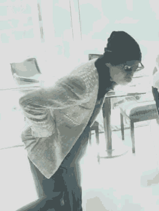 a woman wearing a beanie and glasses is standing in front of a table .