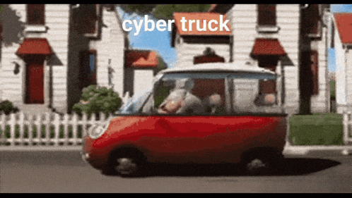 a red car is driving down a street with the words cyber truck written on the roof