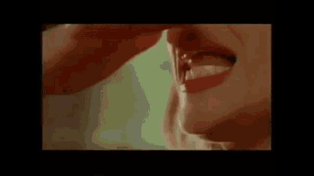 a close up of a woman 's mouth with red lips and a man 's hand .