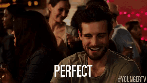 a man with a beard is sitting at a table with the word perfect written on it