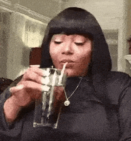 a woman is drinking from a glass through a straw .
