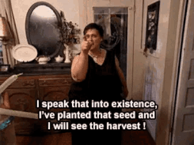 a woman is pointing at the camera in a living room while talking about planting seeds and harvest .