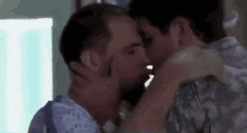 a man in a hospital gown kisses another man on the cheek