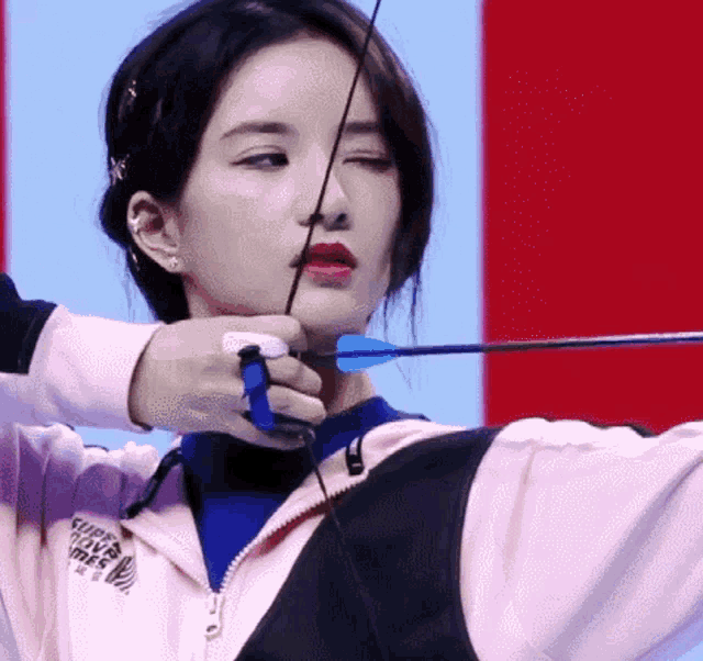 a woman is holding a bow and arrow while wearing a jacket that says ' survival ' on it