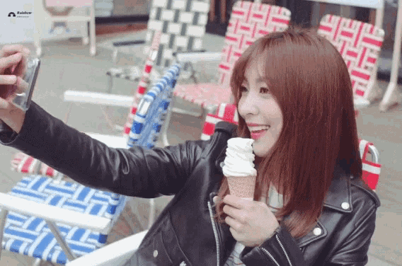 a woman taking a selfie while holding an ice cream cone with the word rainbow on it