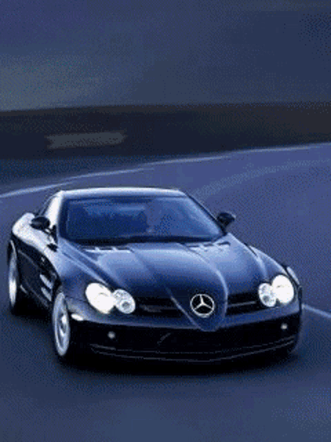 a mercedes car is driving down a road with its headlights on
