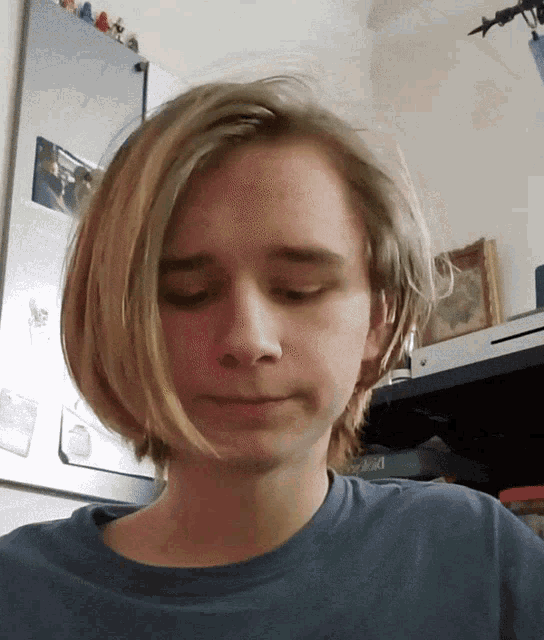 a young man with a blue shirt on looks down at something
