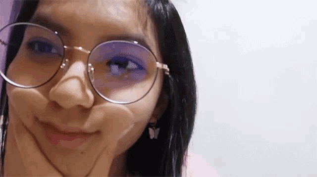 a close up of a woman wearing glasses and earrings making a funny face .