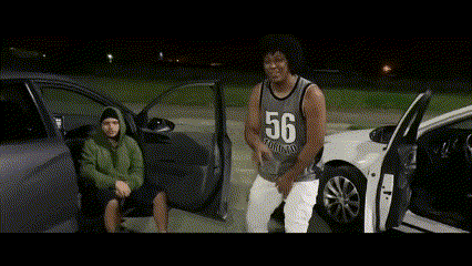 a man wearing a number 56 jersey is standing next to a car .