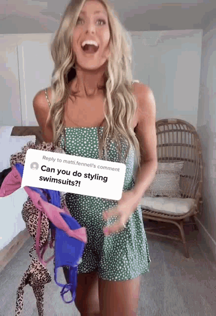 a woman in a green dress is holding a bunch of swimsuits in front of a wicker chair
