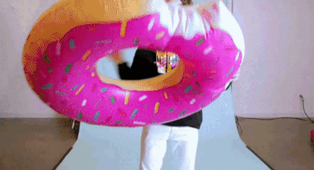 a person is holding a pink donut shaped float with sprinkles on it