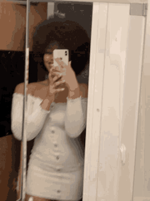 a woman is taking a selfie in front of a mirror .